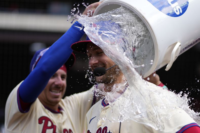 Trea Turner de los Filis de Filadelfia es bañado por Bryson Stott tras la victoria de su equipo ante los Marlins de Miami el domingo 30 de junio del 2024. (AP Foto/Matt Slocum)