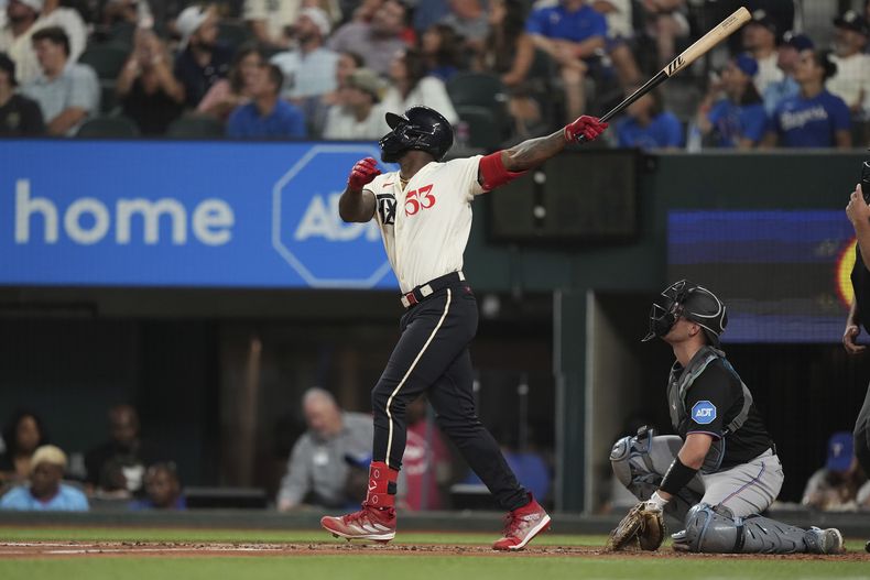 Adolis Garcia (53), de los Rangers de Texas, y el receptor de los Marlins de Miami, Nick Fortes, observan el jonrón solitario de García durante la tercera entrada del juego del béisbol en Arlington, Texas, el viernes 4 de agosto de 2023. (AP Foto/LM Otero)