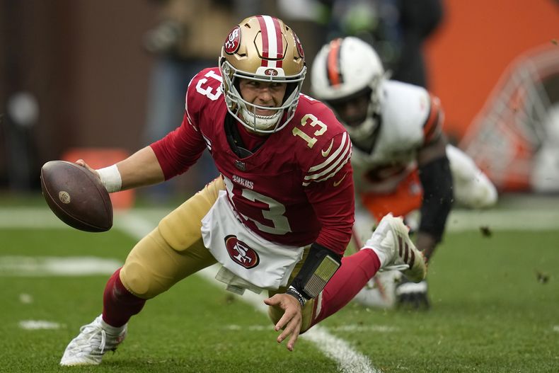 El quarterback de los 49ers de San Francisco Brock Purdy (13) escapa del linebacker de los Browns de Cleveland Jeremiah Owusu-Koramoah durante la 2da mitad del juego de NFL en Cleveland, el domingo 15 de octubre de 2023. (AP Foto/Sue Ogrocki)