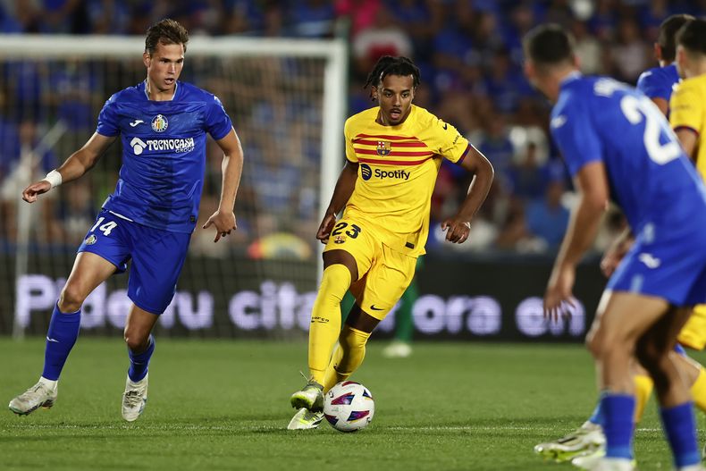 El defensa del Barcelona Jules Kounde (centro) y Juanmi Latasa (izquierda) del Getafe pugnan por el balón en el partido de La Liga española, el domingo 13 de agosto de 2023. (AP Foto/Álvaro Medranda)