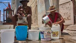 Oscar Joaquín López (izquierda) y su compañero de casa, Wilfredo Cisneros Duarte, recogen agua de una tubería en la calle en La Habana, Cuba, el 7 de septiembre de 2026. (AP Foto/Ramón Espinosa)