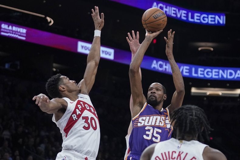 El alero de los Suns de Phoenix, Kevin Durant (35), dispara sobre el escolta de los Raptors de Toronto , Ochai Agbaji (30), durante la segunda mitad deL partido de baloncesto de la NBA en Phoenix, el jueves de marzo. 7, 2024. Phoenix ganó 120-113. (AP Foto/Darryl Webb)