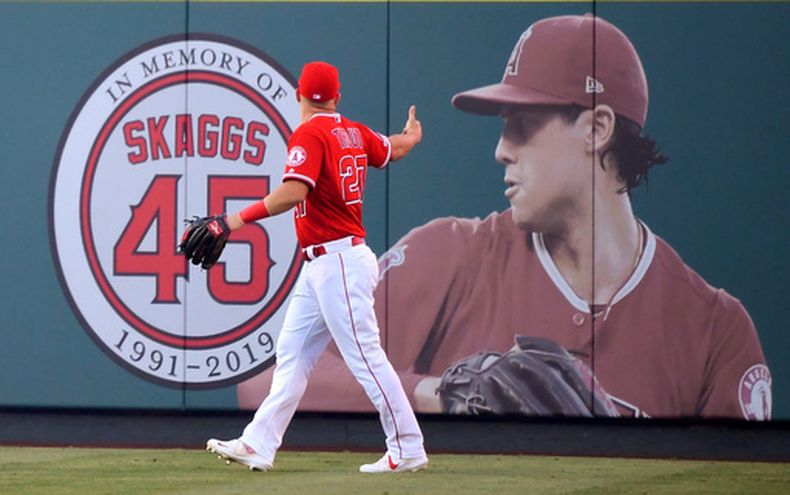 ARCHIVO - El jardinero central de los Angelinos de Los Ángeles, Mike Trout, señala una foto de Tyler Skaggs en el jardín central antes de un partido de béisbol en contra los Tigres de Detroit en Anaheim, California, el 29 de julio de 2019. (Foto AP/Mark J. Terrill, Archivo)