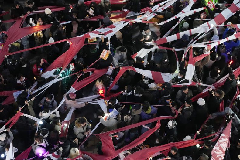 Participantes desgarran una pancarta que representa una bandera del Partido del Poder Popular, durante una marcha para reclamar la destitución del presidente de Corea del Sur, Yoon Suk Yeol, ante la sede del gobernante PPP en Seúl, Corea del Sur, el lunes 9 de diciembre de 2024. (AP Foto/Ahnn Young-joon)