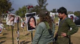 Soldados israelíes miran fotos de personas muertas o en cautiverio de Hamás durante el ataque de los milicianos al festival musical Nova en el sur de Israel, exhibidas en el lugar del hecho para conmemorar la masacre del 7 de octubre, cerca del kibbutz Reim, viernes 1 de diciembre de 2023. (AP Foto/Ariel Schalit)