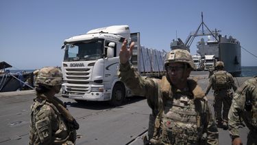 Un soldado del ejército de Estados Unidos hace señas al conductor de un camión cargado con asistencia humanitaria a su llegada al muelle flotante Trident, construido por Estados Unidos, antes de llegar a la playa en la costa de la Franja de Gaza, el martes 25 de junio de 2024. (AP Foto/Leo Correa)