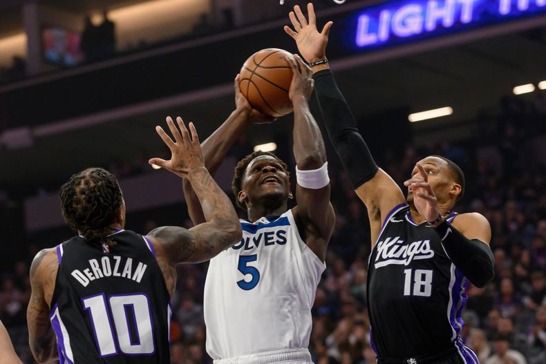 Anthony Edwards (5), de los Timberwolves de Minnesota, ataca la canasta con la presión defensiva de DeMar DeRozan (10) y Russell Westbrook (18), de los Kings de Sacramento, durante la primera mitad del juego de baloncesto de la NBA, el lunes 24 de noviembre de 2025. (AP Foto/Randall Benton)