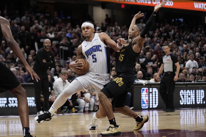 El alero del Magic de Orlando Paolo Banchero avanza hacia la canasta superando al alero de los Cavaliers de Cleveland Isaac Okoro en el juego 7 de la serie de primera ronda de la postemporada del domingo 5 de mayo del 2024. (AP Foto/Sue Ogrocki)