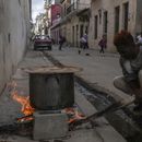 Un hombre cocina sopa sobre una fogata en una acera durante un apagón en La Habana, Cuba, el miércoles 4 de diciembre de 2024. (AP Foto/Ramón Espinosa)