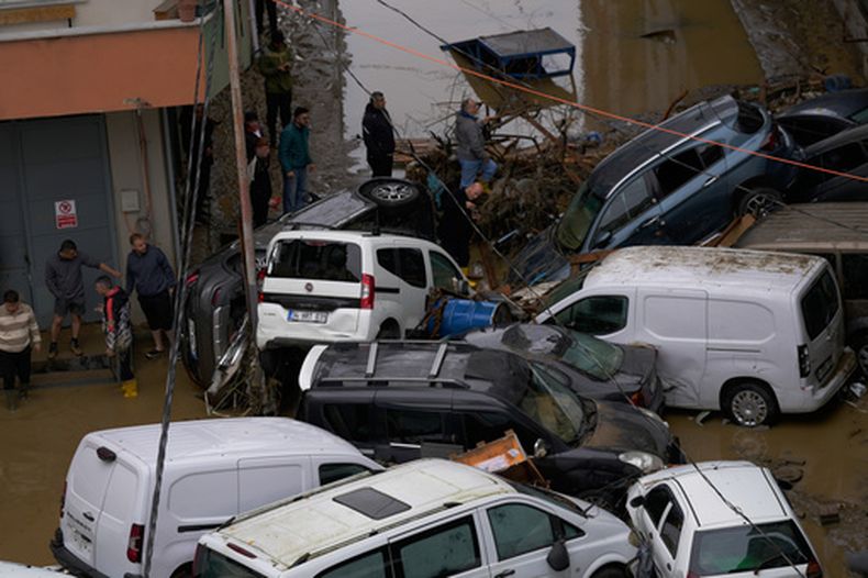 Residentes pasan junto a autos y escombros acumulados tras las inundaciones causadas por las intensas lluvias caídas en Estambul, Turquía, el 15 de octubre de 2026. (AP Foto/Emrah Gurel)