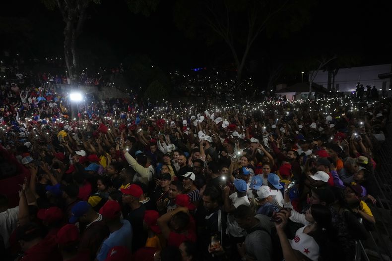Seguidores del presidente Nicolás Maduro encienden luces con sus teléfonos mientras un cantante actúa en un escenario, durante la espera de resultados de las elecciones presidenciales en Caracas, Venezuela, el domingo 28 de julio de 2024. (AP Foto/Fernando Vergara)