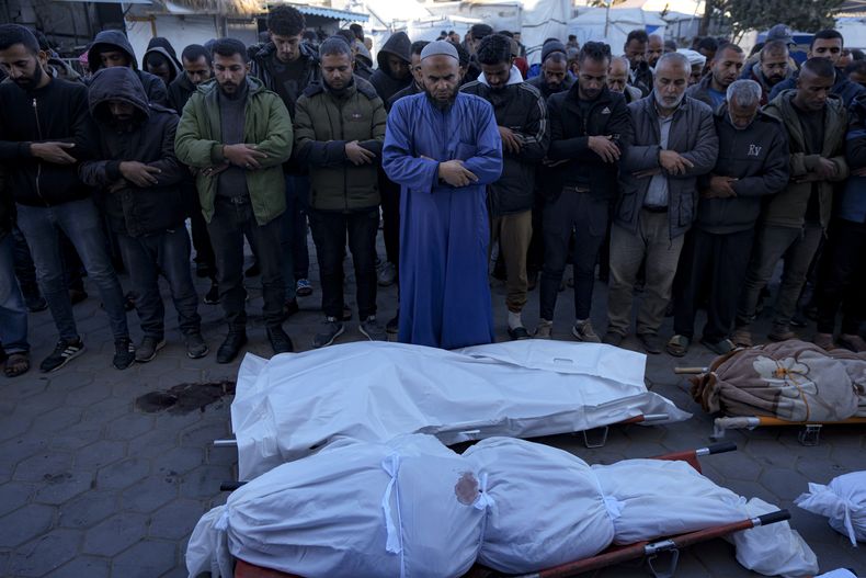 Palestinos rezan junto a los cuerpos de sus familiares muertos en el bombardeo israelí de la Franja de Gaza en un hospital de Deir al-Balah, el domingo 15 de diciembre de 2024. (AP Foto/Abdel Kareem Hana)