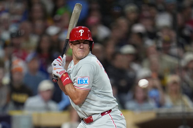 ARCHIVO - J.T. Realmuto, de los Filis de Filadelfia, se encoge para tratar de protegerse antes de ser golpeado por un lanzamiento durante la octava entrada del juego de béisbol de Grandes Ligas contra los Padres de San Diego, el martes 26 de mayo de 2026, en San Diego. (AP Foto/Gregory Bull)