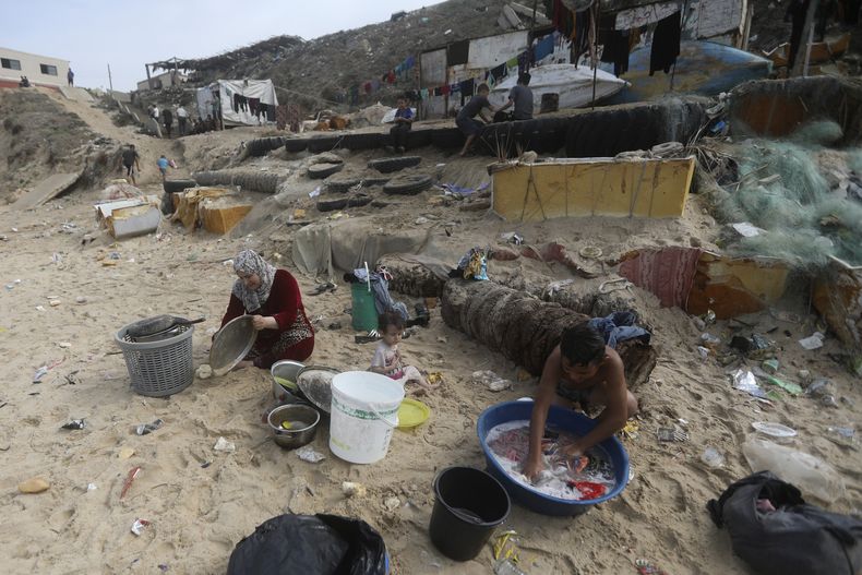 ARCHIVOS- Palestinos se bañan y lavan sus herramientas en agua salada debido a la escasez de agua en la Franja de Gaza, en la playa de Deir al-Balah, Franja de Gaza, 29 de octubre de 2023. (AP Foto/Mohammed Dahman, File)