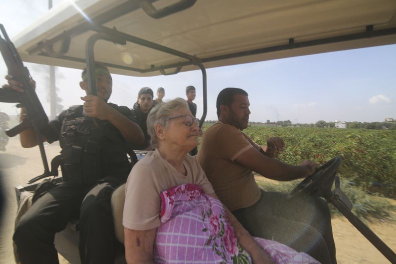 Palestinos transportan a una civil israelí capturada, centro, del kibbutz Kfar Azza a la Franja de Gaza, sábado 7 de octubre de 2023. (AP Foto)