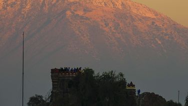 ARCHIVO - El sol del atardecer ilumina Los Andes con una capa de nieve mientras visitantes toman fotos desde Santa Lucía, en Santiago, Chile, el 8 de mayo de 2024. (AP Foto/Esteban Félix, Archivo)