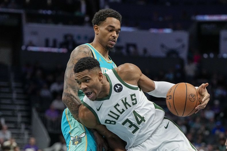 El alero de los Bucks de Milwaukee Giannis Antetokounmpo conduce el balón para superar al alero de los Hornets de Charlotte P.J. Washington durante la primera mitad del juego de NBA el viernes 17 de noviembre de 2023, en Charlotte, Carolina del Norte. (AP Foto/Chris Carlson)