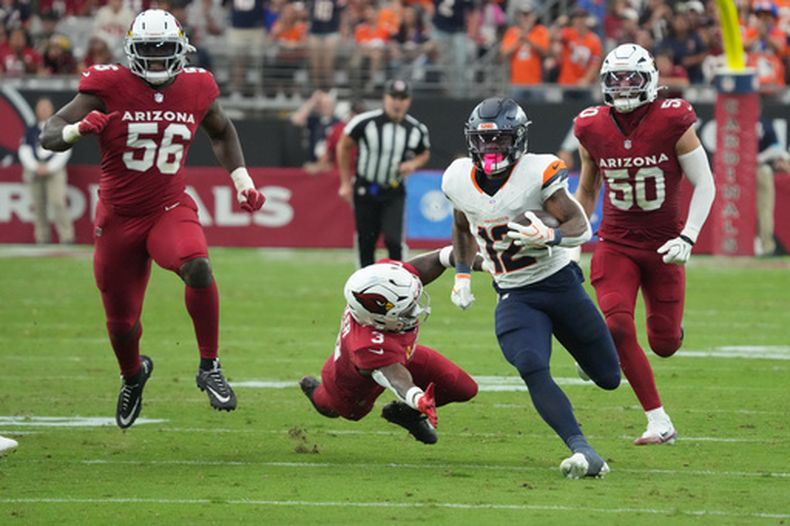 RJ Harvey (12), corredor de los Broncos de Denver, lleva el balón hacia la zona de anotación superando a Budda Baker (3), profundo de los Cardinals de Arizona, durante la segunda mitad del partido de la NFL del domingo 25 de octubre de 2026, en Glendale, Arizona. (AP Foto/Rick Scuteri)