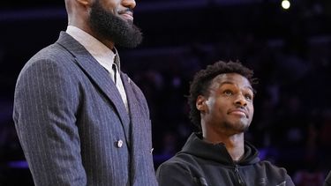ARCHIVO - LeBron James (izquierda) y su hijo Bronny escuchan una ceremonia donde se honra al primero como líder anotador en la historia de la NBA, el 9 de febrero de 2023 (AP Foto/Mark J. Terrill)