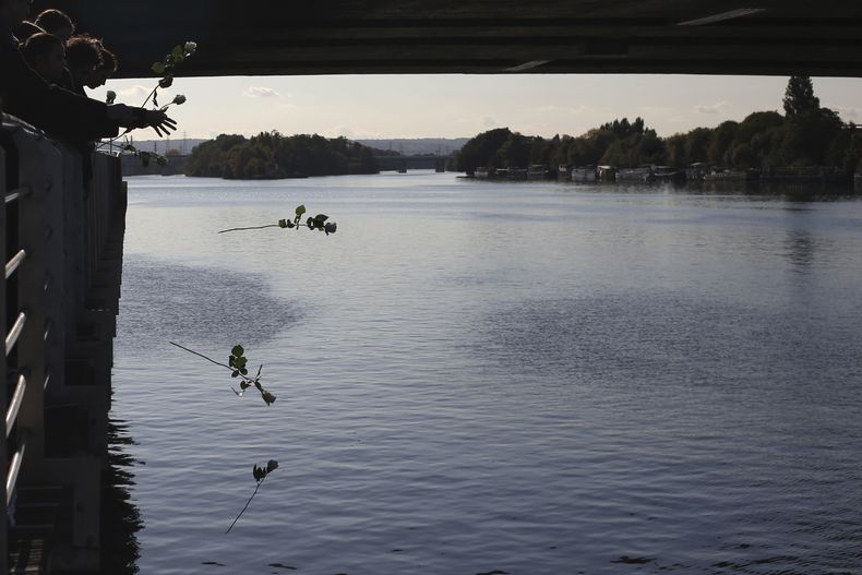 ARCHIVO - Invitados arrojan rosas al río Sena después de que el presidente francés Emmanuel Macron colocó una corona cerca del Pont de Bezons el sábado 16 de octubre de 2021 en Colombes, cerca de París. (AP Foto/Rafael Yaghobzadeh, Pool, Archivo)