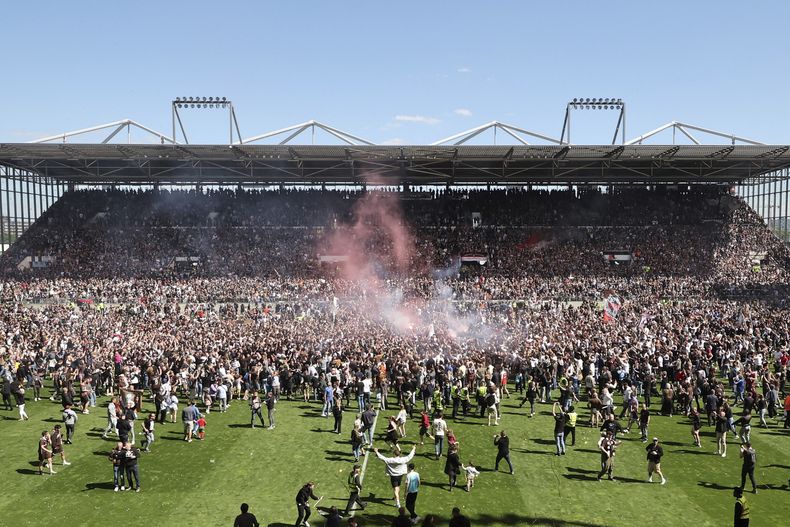Los hinchas de St. Pauli irrumpen en la cancha tras vencer 3-1 a Osnabrück y lograr el ascenso a la Bundesliga, el domingo 12 de mayo de 2024, en Hamburgo. (Christian Charisius/dpa vía AP)