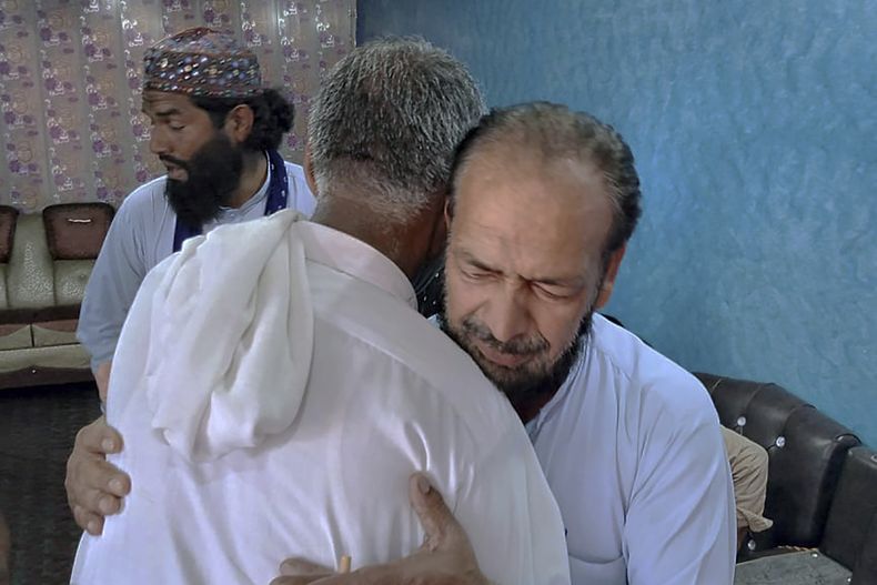 Personas ofrecen su apoyo a Raja Yousaf, cuyo hijo Raja Sajid desapareció luego de un naufragio frente a la costa griega, en la localidad de Bindian, Pakistán, el domingo 18 de junio de 2023. (AP Foto/Nasir Mehmood)