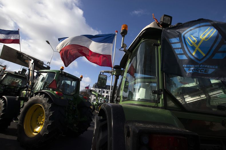 ARCHIVO - La bandera de la Fuerza de Defensa de los Agricultores, a la derecha, y banderas holandesas, ondean en un cruce bloqueado por tractores en La Haya, Holanda, el miércoles 19 de febrero de 2020. (AP Foto/Peter Dejong, Archivo)