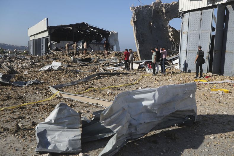Un grupo de personas se congregan junto a un hangar alcanzado por un ataque aéreo israelí, en Jiyeh, Líbano, el 25 de septiembre de 2024. (AP Foto/Mohammed Zaatari)