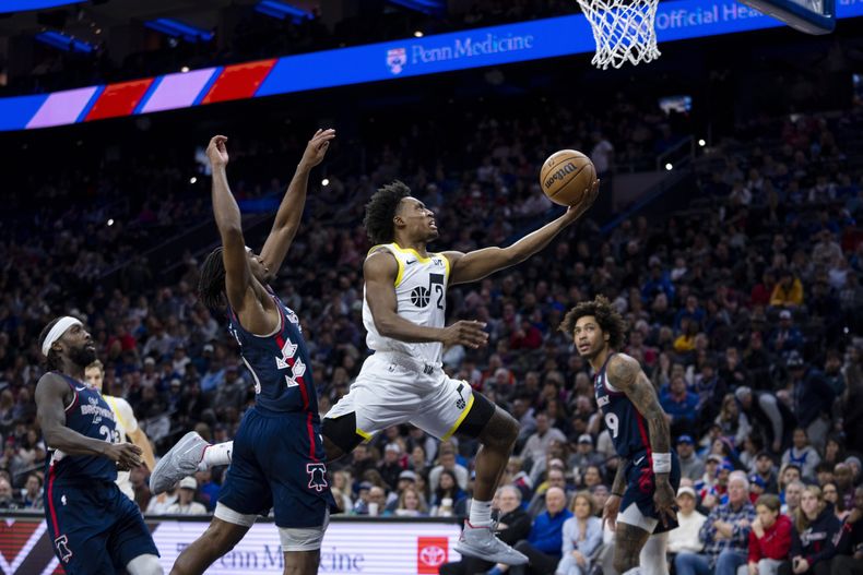 Collin Sexton, del Jazz de Utah, hace una bandeja mientras pasa a Tyrese Maxey, de los 76ers de Filadelfia, del centro a la izquierda, durante la segunda mitad del partido de baloncesto de la NBA, el sábado 6 de enero de 2024, en Filadelfia. El Jazz ganó 120-109. (AP Foto/Chris Szagola)