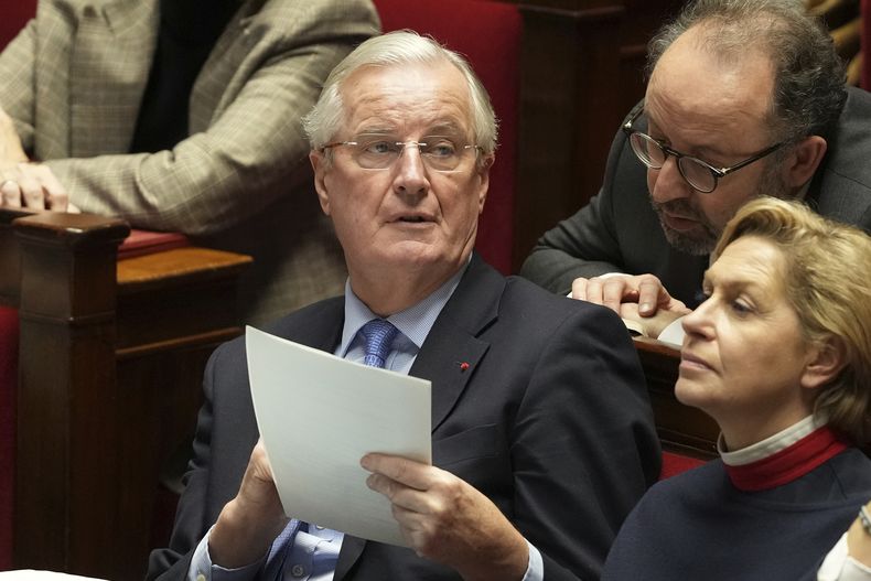 El primer ministro francés, Michel Barnier, sostiene un documento durante los discursos en la Asamblea Nacional antes de un voto de censura, el miércoles 4 de diciembre de 2024 en París. (AP foto/Michel Euler)