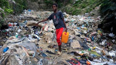 ARCHIVO - Un joven sin agua corriente en casa carga un bidón con agua recogida en un barranco, un día antes del Día Mundial del Agua, en Puerto Príncipe, Haití, el martes 21 de marzo de 2023. (AP Foto/Odelyn Joseph, Archivo)