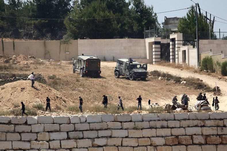 Soldados israelíes hacen guardia junto a colonos frente a viviendas palestinas que estos bloquearon en la localidad de Qusra, al sur de Nablus, en la ocupada Cisjordania, el 12 de agosto de 2026. (AP Foto/Nidal Eshtayeh)