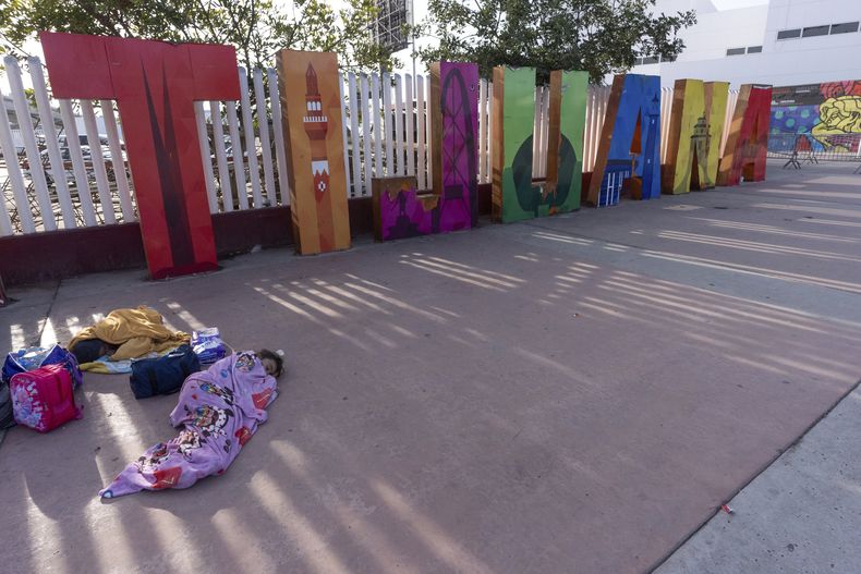 Una menor procedente del estado mexicano de Morelia, duerme frente a un cartel con el nombre de Tijuana mientras las citas solicitadas por su familia a través de la app CBP One para pedir asilo en Estados Unidos fueron declaradas no válidas, el 20 de enero de 2025, en Tijuana, México, poco después de la investidura de Donald Trump como presidente de Estados Unidos. (AP Foto/Gregory Bull)