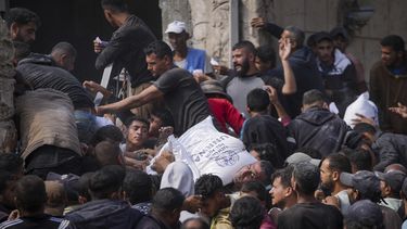 Palestinos se reúnen para recibir bolsas de harina distribuidas por la UNRWA, la agencia de la ONU que ayuda a los refugiados palestinos, en Deir al Balah, en el centro de la Franja de Gaza, el sábado 2 de noviembre de 2024. (AP Foto/Abdel Kareem Hana)