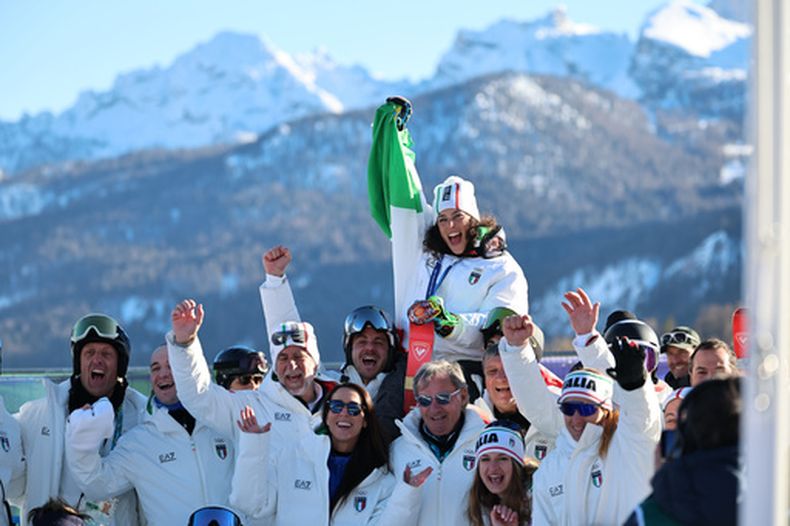 La italiana Federica Brignone muetra su medalla de oro mientras celebra con sus compañeros tras ganar el eslalon gigante en los Juegos Olímpicos de Invierno en Cortina dAmpezzo, Italia el domingo 15 de febrero del 2026. (AP Foto/Marco Trovati)