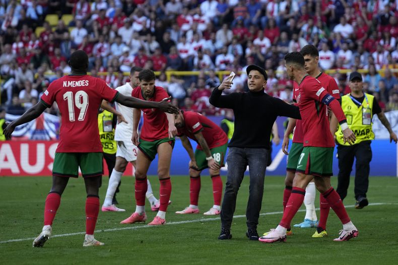 Un invasor de campo intenta tomarse una fotografía con el delantero de Portugal Cristiano Ronaldo en el encuentro ante Turquía del Grupo F el sábado 22 de junio del 2024. (AP Foto/Themba Hadebe)