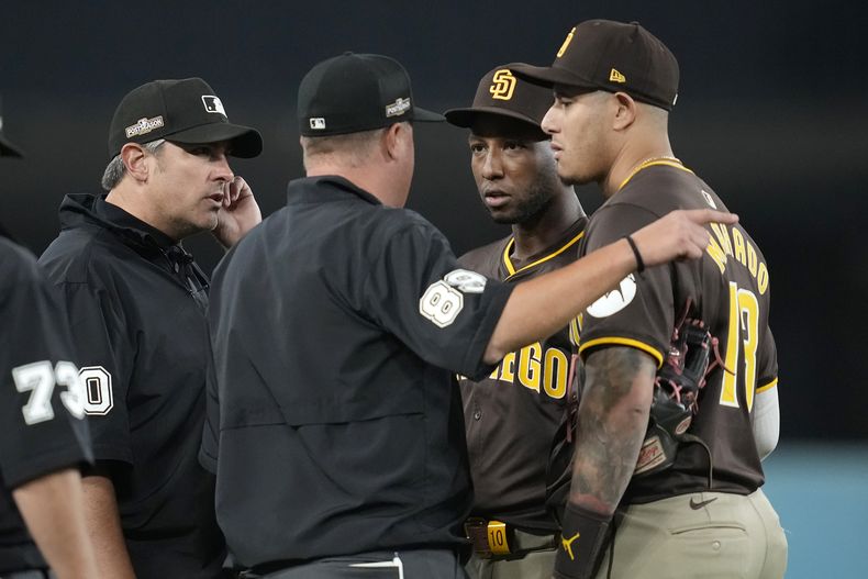 El jardinero izquierdo de los Padres de San Diego, Jurickson Profar, segundo desde la derecha, y el tercera base Manny Machado hablan con los umpires después de que se lanzaron objetos a Profar en los jardines durante la séptima entrada en el Juego 2 de una Serie Divisional de la Liga Nacional contra los Dodgers de Los Ángeles, el domingo 6 de octubre de 2024, en Los Ángeles. (AP Foto/Ashley Landis)