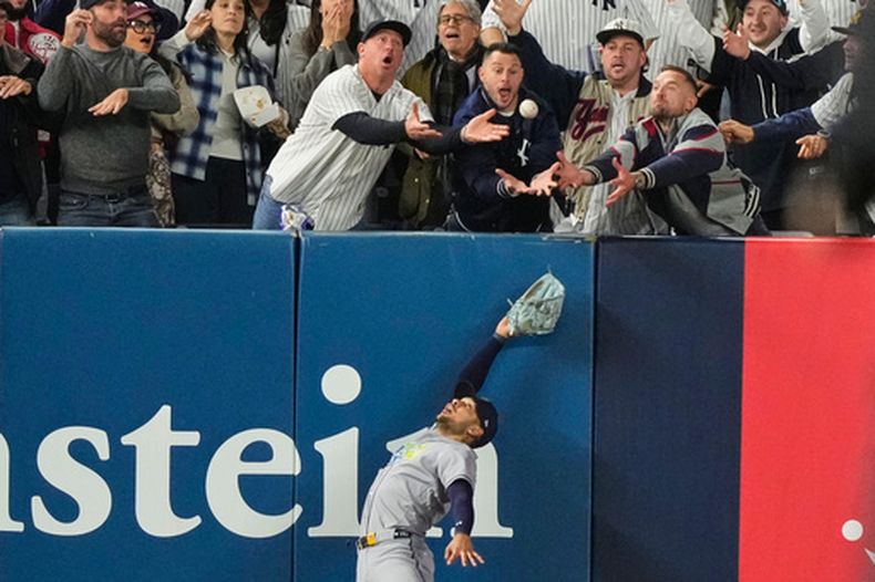 El jardinero izquierdo Víctor Mesa Jr. de los Rays de Tampa Bay trata de atrapar una pelota interferida por fanáticos tras el batazo de Anthony Volpe de los Yankees de Nueva York, en el sexto inning del tercer juego de la serie divisional de la Liga Americana, el miércoles 7 de octubre de 2026, en Nueva York. (AP Foto/Yuki Iwamura)