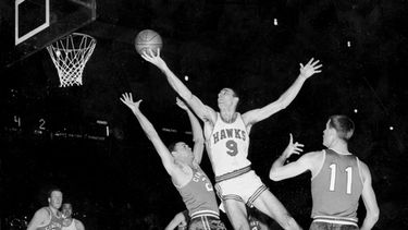 ARCHIVO - En esta foto de archivo del 10 de diciembre de 1957, Bob Pettit, de los Hawks de St. Louis, salta para realizar un disparo a una mano, pero falla en el intento de anotar durante el primer cuarto de un partido de baloncesto de la NBA contra los Royals de Cincinnati en el Madison Square Garden, en la ciudad de Nueva York. Bloqueando a Pettit se encuentra Dick Ricketts (24), de los Royals, mientras Jim Paxson (11) observa la jugada. (Foto AP/Archivo)