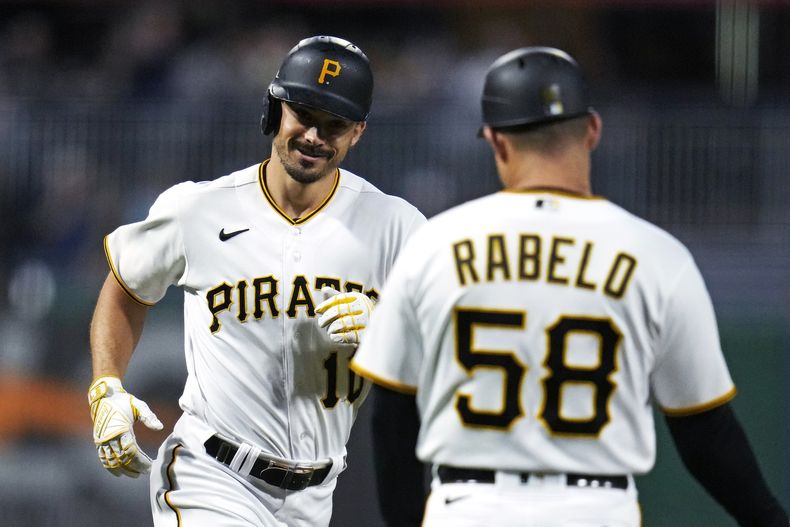 Bryan Reynolds, izquierda, de los Piratas de Pittsburgh, rodea por tercera base mientras es felicitado por el coach de tercera base Mike Rabelo después de batear un cuadrangular de dos carreras ante el abridor de los Nacionales de Washington, Jackson Rutledge, durante la cuarta entrada del juego de béisbol en Pittsburgh, el miércoles 13 de septiembre de 2023. (AP Foto/Gene J. Puskar)