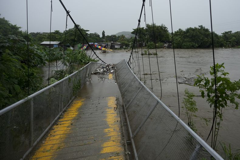 Un puente peatonal colapsado debido a las inundaciones causadas por las lluvias provocadas por la tormenta tropical Sara en San Pedro Sula, Honduras, el sábado 16 de noviembre de 2024. (AP Foto/Moisés Castillo)