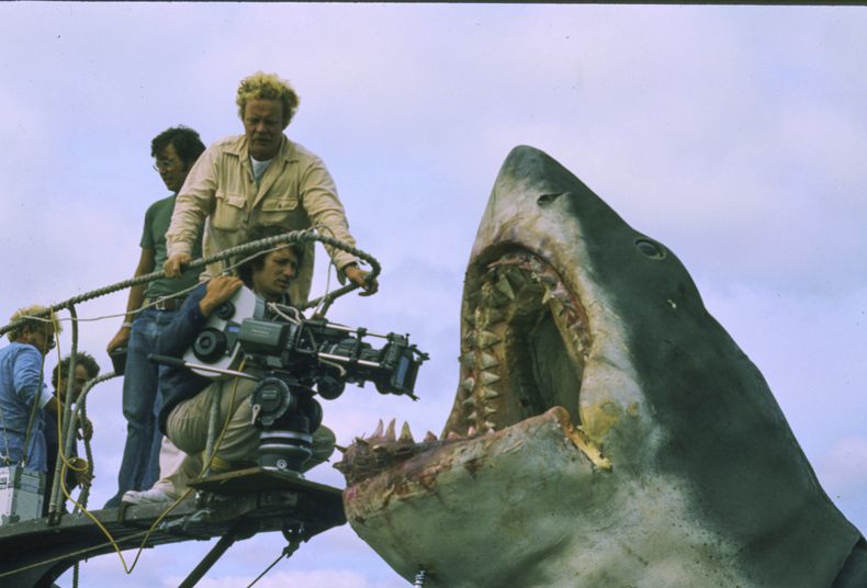 Esta imagen publicada por Peacock muestra al director de fotografía Bill Butler, de pie, y al director Steven Spielberg durante el rodaje de Jaws. (Peacock/Universal Pictures via AP)
