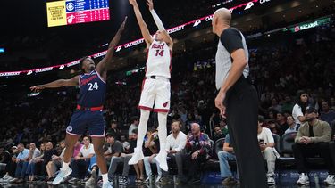 Tyler Herro (14), del Heat de Miami, dispara un triple mientras Kobe Brown (24), de los Clippers de Los Ángeles, defiende durante la primera mitad del juego de baloncesto de la NBA, el lunes 1 de diciembre de 2025, en Miami. (AP Foto/Lynne Sladky)