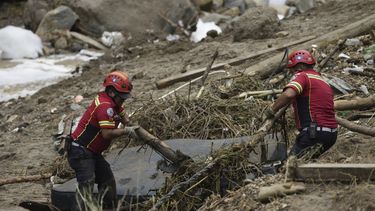 Los bomberos limpian los escombros mientras buscan sobrevivientes donde las casas fueron arrasadas por la crecida del río El Naranjo después de fuertes lluvias en las afueras de la ciudad de Guatemala, el lunes 25 de septiembre de 2023. (AP Foto/Moisés Castillo)