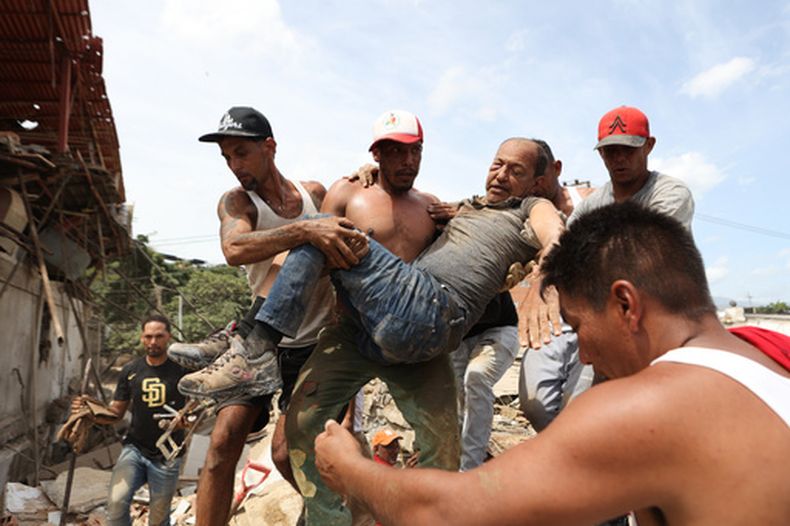 Unos vecinos transportan a un hombre rescatado de entre los escombros de un edificio derrumbado un día después de que los terremotos azotaran La Guaira, Venezuela, el jueves 25 de junio de 2026. (Foto AP/Pedro Mattey)