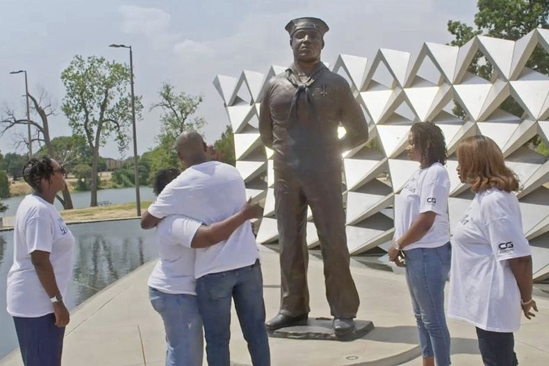En esta imagen proporcionada por National Geographic familiares rodean una estatua en honor al asistente de comedor Doris Miller en Waco, Texas. Miller, derribó aviones enemigos durante el ataque de Pearl Harbor, su historia es retratada en la serie documental Erased: WW2s Heroes of Color. (National Geographic vía AP)