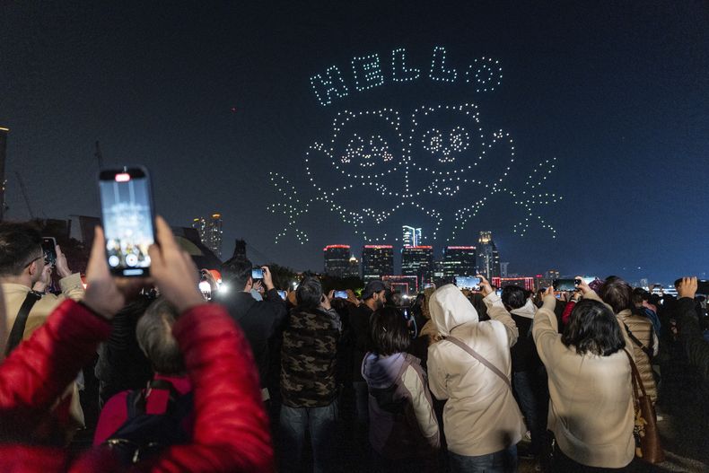 La gente observa el espectáculo de drones con temática de pandas en el puerto Victoria, en Hong Kong, el 28 de diciembre de 2024. (AP Foto/Chan Long Hei)