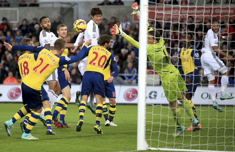 El arquero de Arsenal Wojciech Szczesny rechaza ante un ataque de Swansea en partido de la Liga Premier en Swansea, Gales, el 9 de noviembre del 2014. Swansea gan&oacute; 2-1. (AP Foto/Nick Potts/PA)  UNITED KINGDOM OUT