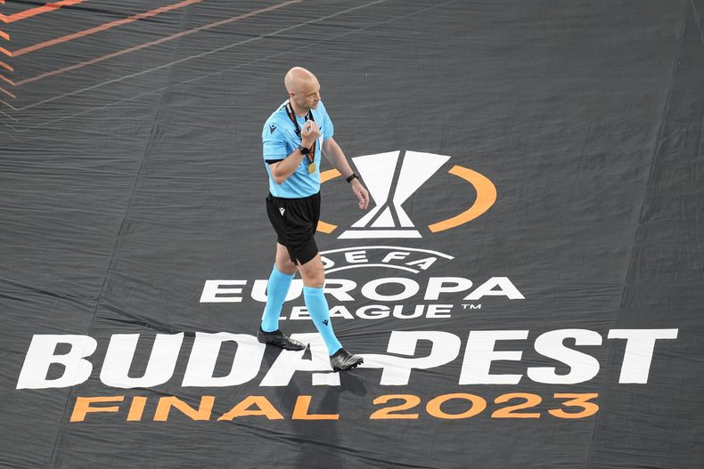 El árbitro británico Anthony Taylor camina sobre una manta luego de dirigir la final de la Liga Europa entre Sevilla y Roa, el miércoles 31 de mayo de 2023, en Budapest (AP Foto/Darko Vojinovic)
