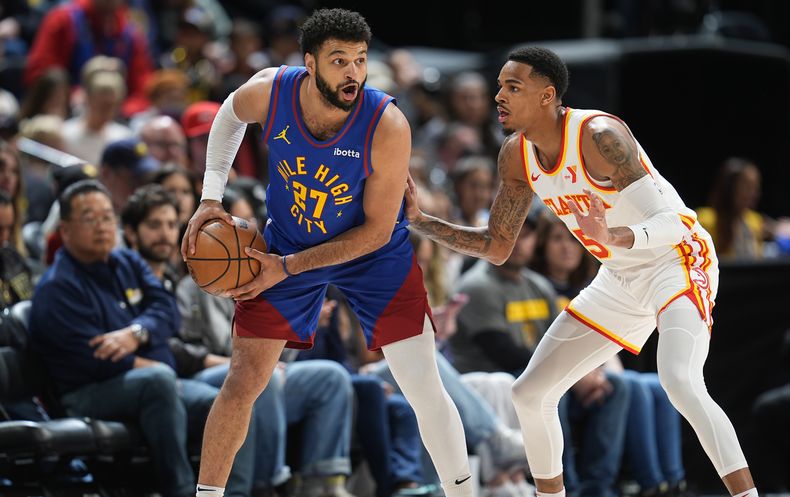 El armador de los Nuggets de Denver Jamal Murray (27) busca a quien pasar la bola mientras es defendido por el base de los Hawks de Atlanta Dejounte Murray durante la primera mitad del juego de baloncesto de la NBA, el sábado 6 de abril de 2024, en Denver. (AP Foto/David Zalubowski)